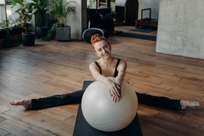 Full length of young woman lying on hardwood floor