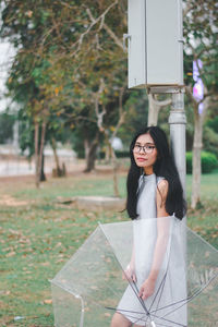 Portrait of young woman standing against plants