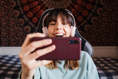 Smiling young woman video conferencing over mobile phone