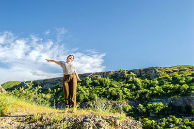 Rear view of woman standing on mountain against sky