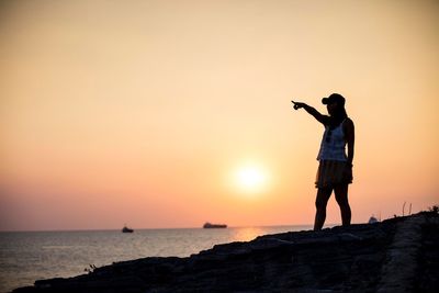 Man photographing sea against sky during sunset