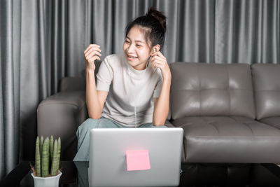 Full length of young woman sitting on sofa