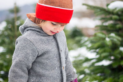 Portrait of young kid standing against trees in winter