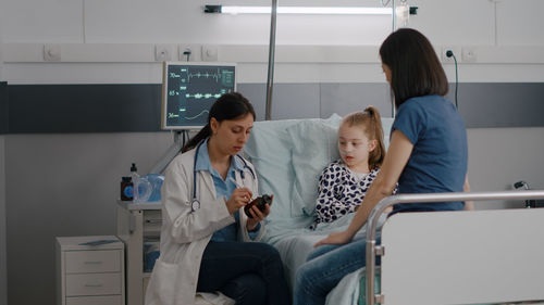 Doctor having discussion with mother and daughter at hospital