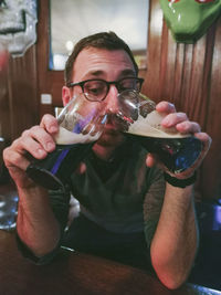 Portrait of man drinking glass on table