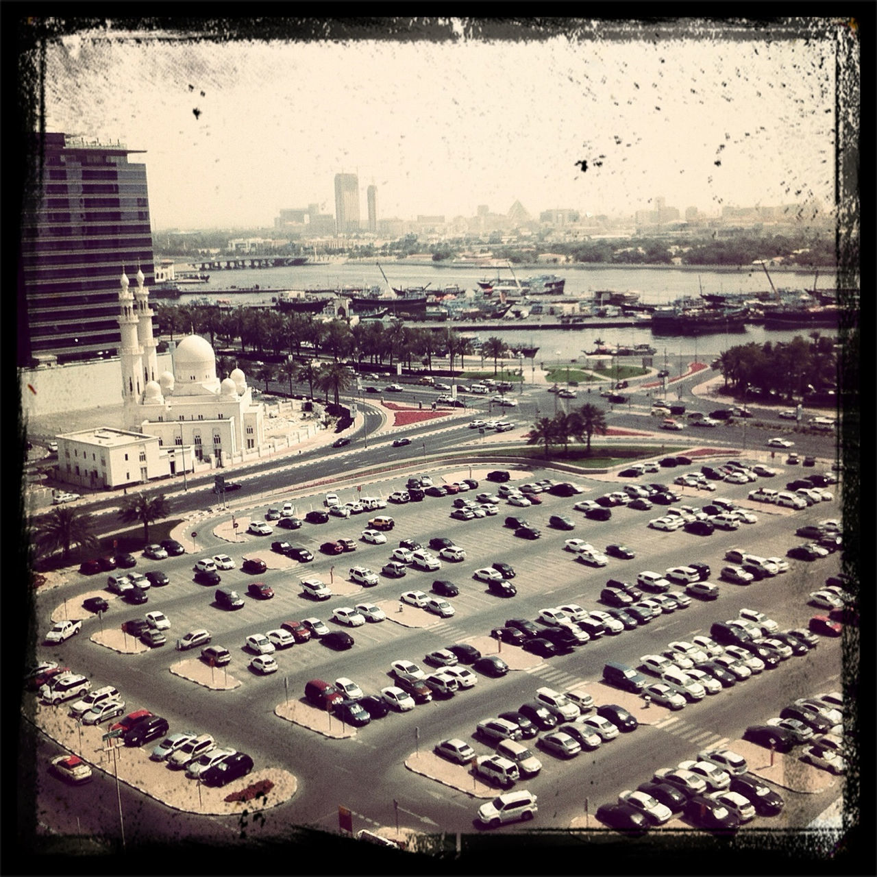 city, high angle view, transportation, building exterior, car, architecture, street, land vehicle, built structure, road, city life, mode of transport, large group of people, transfer print, traffic, auto post production filter, cityscape, city street, road marking, day