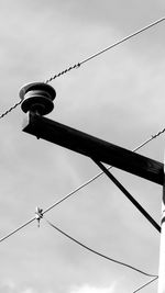 Low angle view of power cables against cloudy sky