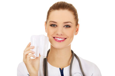 Portrait of female doctor holding dentures against white background
