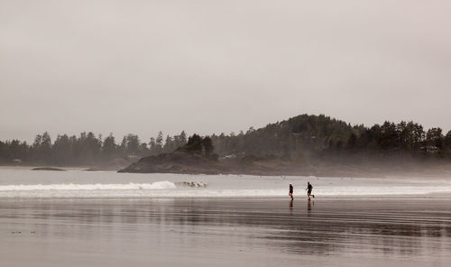 People running at beach against sky