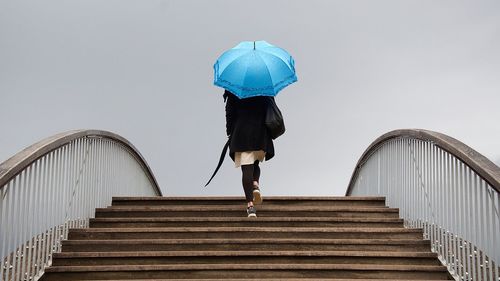 Rear view of woman walking on staircase against clear sky