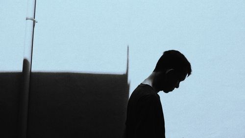 Side view of sad man standing by wall