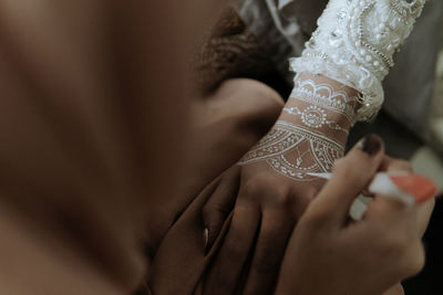 Cropped image of woman applying henna tattoo on bride hands