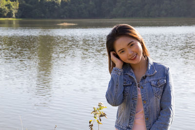 Portrait of smiling woman standing against lake