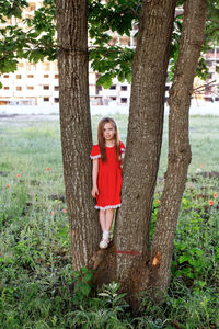 Portrait of a smiling young woman standing on tree trunk