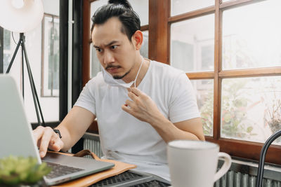 Young man using phone while sitting on table