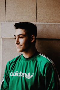 Portrait of young man looking away against wall