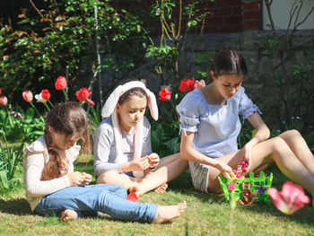 Three caucasian girl sisters eat easter candy on the lawn.