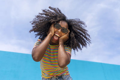 Portrait of woman touching cheek against sky