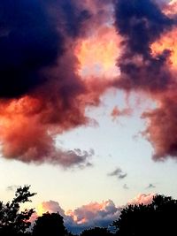 Low angle view of silhouette trees against dramatic sky