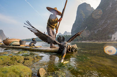 Man standing on wooden raft fishing in lake