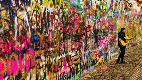 Full length of man standing against graffiti wall