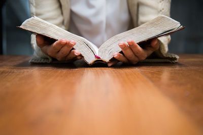 Midsection of woman reading book at table