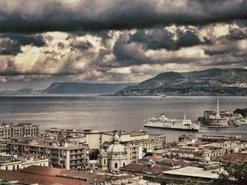 View of town by sea against cloudy sky