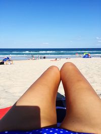 Low section of woman in bikini sitting on beach