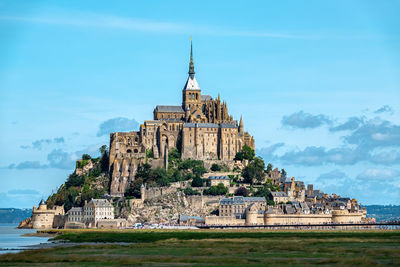 Buildings by sea against sky