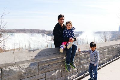 Man sitting on retaining wall with girl and boy