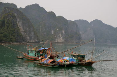 Boats sailing in sea against mountains