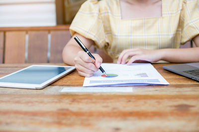 Midsection of woman using mobile phone on table