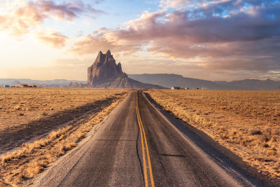 Road amidst land against sky during sunset