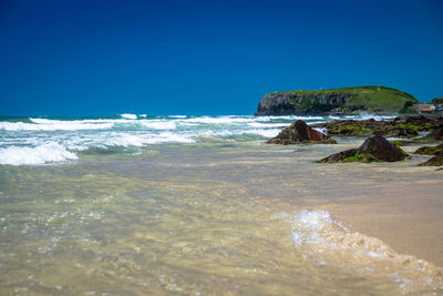 Scenic view of beach against clear blue sky