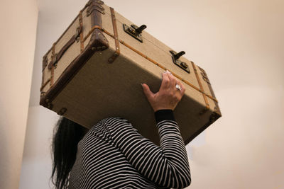 Close-up of woman carrying suitcase on shoulders