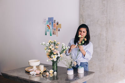 Portrait of  woman creating a flower arrangement  in a marble table 