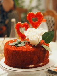 Festive cake, decorated in the style of a ruby wedding, with red hearts and delicate roses.