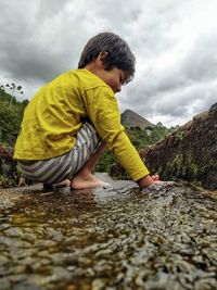 Rear view of boy in water against sky