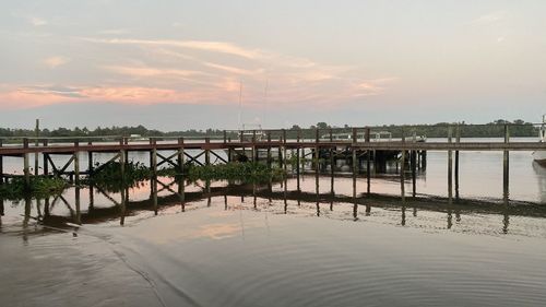 Pier over sea against sky during sunset