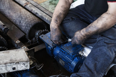 Midsection of man working on machinery in factory