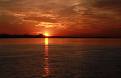 Scenic view of sea against dramatic sky during sunset