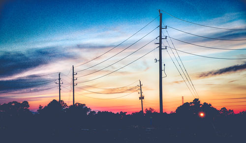 Low angle view of electricity pylon against cloudy sky