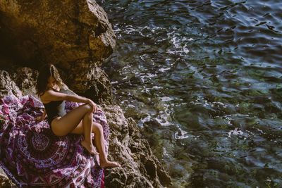 Woman standing on rock formation in water