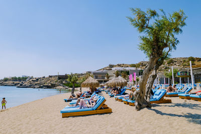 People on beach against clear blue sky