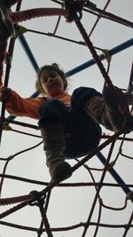 Low angle view of girl playing on jungle gym in playground