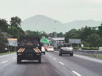 Cars on road against sky in city