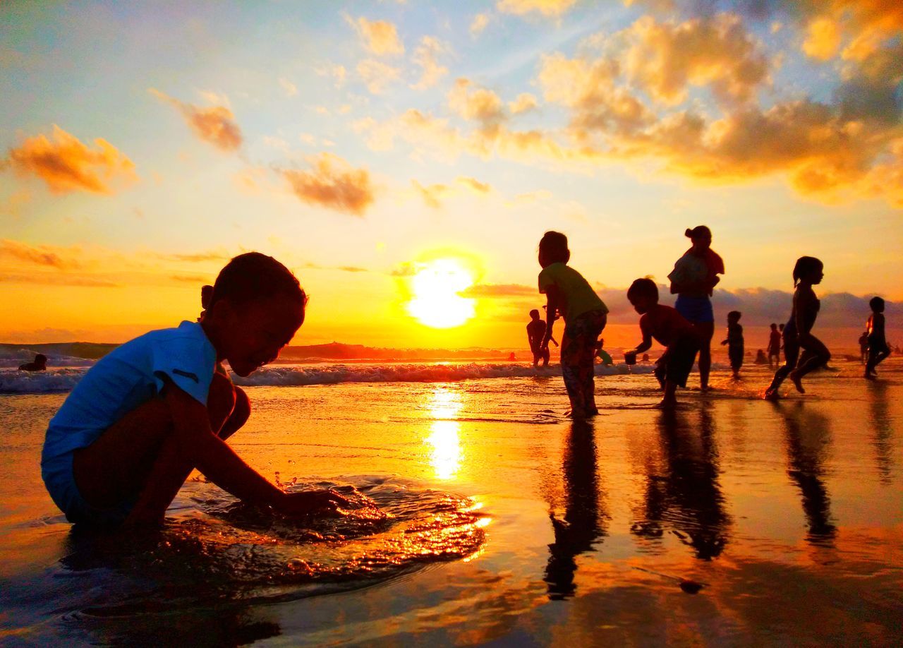 sunset, water, sky, beach, nature, sea, group of people, men, orange color, child, land, childhood, reflection, silhouette, ocean, sunlight, cloud, adult, horizon, evening, fun, sun, beauty in nature, dusk, leisure activity, togetherness, shore, lifestyles, holiday, summer, wave, enjoyment, trip, back lit, vacation, women, emotion, coast, friendship, outdoors, sports, motion, sand, happiness, positive emotion