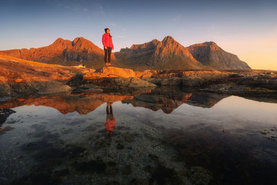 Reflection of man standing on rock against sky