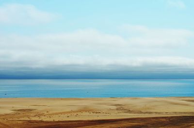 Scenic view of beach against cloudy sky