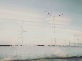 Windmills on field against sky